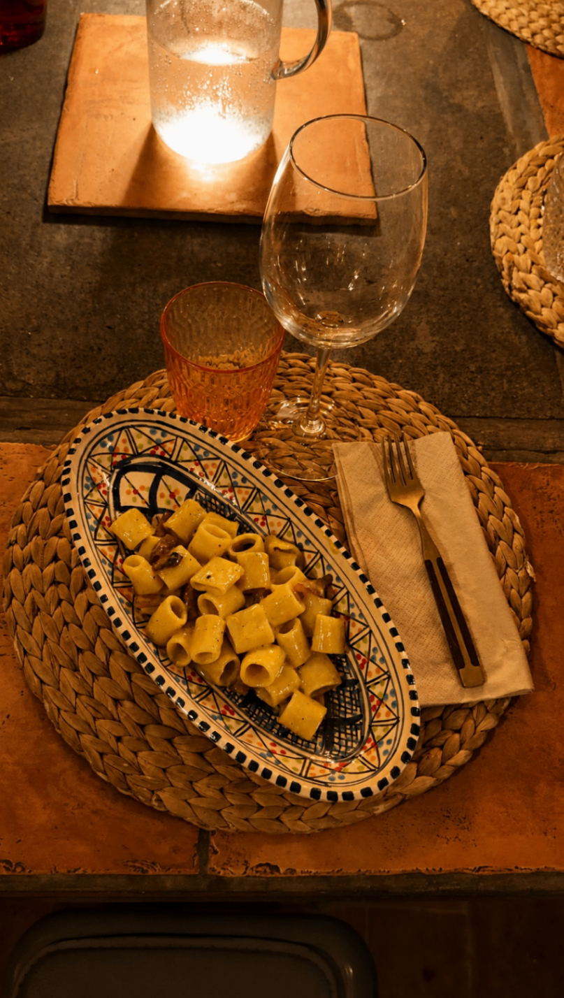 A bowl of carbonara plated at a candlelit place setting